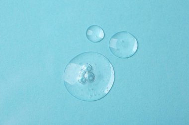 Açık mavi zemin üzerinde kozmetik serumu örnekleri, düz yatıyordu