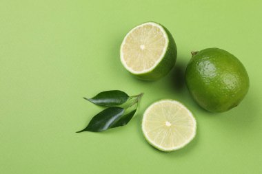 Yeşil arka planda taze limon ve yapraklarla bezenmiş düz bir kompozisyon. Metin için boşluk