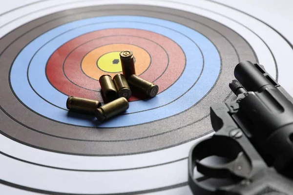 Handgun and bullets on shooting target, closeup
