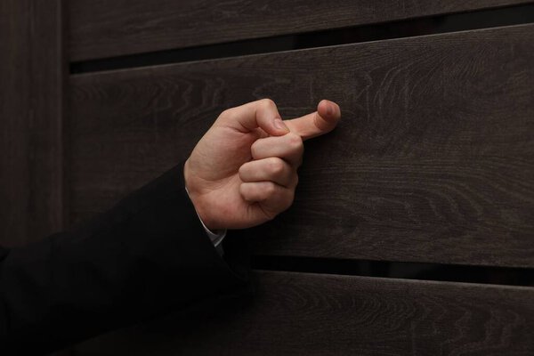 Collector knocking on door indoors, closeup view