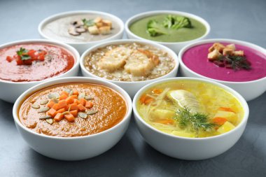 Lezzetli et suyu ve farklı krema çorbaları gri masada, yakın plan.