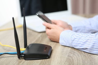 Akıllı telefonu olan bir kadın internete Wi-Fi yönlendiricisiyle bağlanıyor.