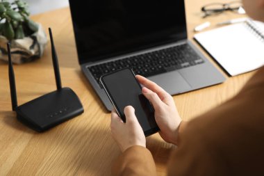 Akıllı telefonu olan bir kadın internete Wi-Fi yönlendiricisiyle bağlanıyor.