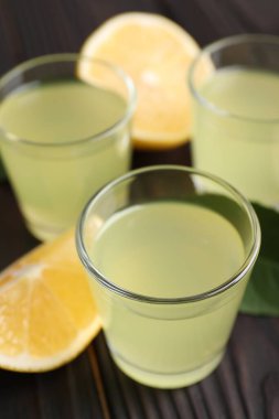 Lezzetli limoncello likörü ve limon koyu ahşap masada, yakın plan.