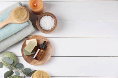 Farklı spa ürünleri ve beyaz ahşap masada yanan mum içeren düz bir kompozisyon. Metin için boşluk