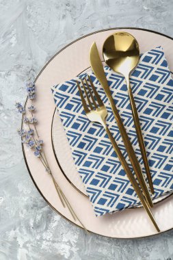 Temiz tabaklar, çatal bıçak takımı, peçete ve lavanta çiçekleri açık gri desenli masa, üst manzara