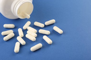 Mavi arka planda şişe ve vitamin kapsülleri, yakın plan. Metin için boşluk