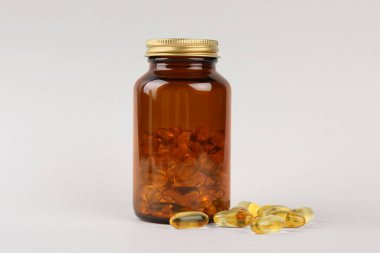 Açık gri arkaplanda vitamin kapsüllü kavanoz
