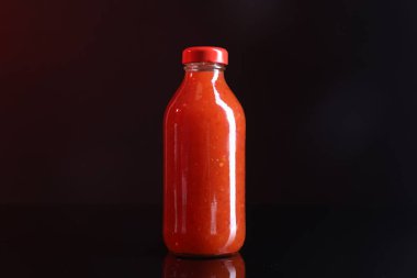 Şişedeki acı biber sosu koyu arka planda.