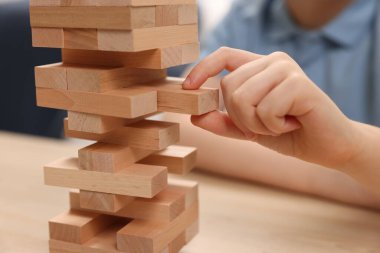 Çocuk içeride ahşap masada Jenga oynuyor, yakın plan.