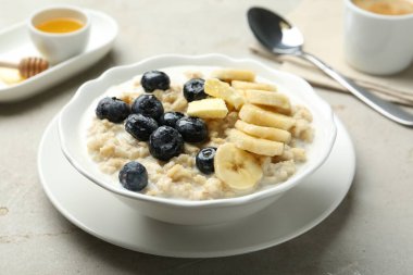 Muzlu, yabanmersinli, tereyağlı ve sütlü lezzetli yulaf ezmesi açık gri masada servis edilir.