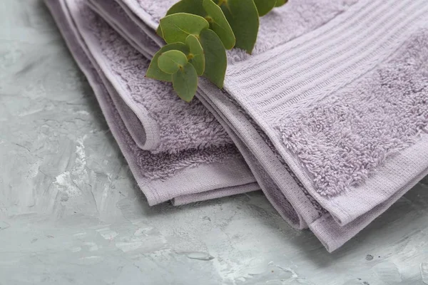 Violet terry towel and eucalyptus branch on grey table, closeup