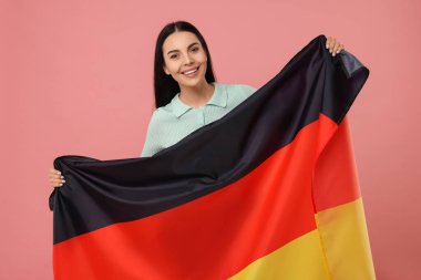 Pembe arka planda Almanya bayrağı taşıyan mutlu genç bir kadın.