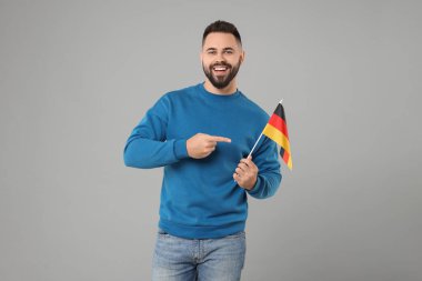 Açık gri arka planda Almanya bayrağı taşıyan genç adam