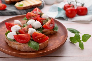Mozzarella, domates, fesleğen ve pesto soslu leziz Caprese sandviçleri beyaz ahşap masada, yakın plan.