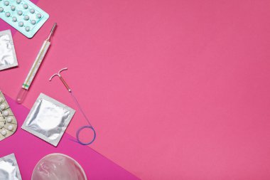 Doğum kontrol hapları, prezervatifler, rahim içi cihazlar ve renkli arka plan termometresi, düz yatak ve metin için alan. Farklı doğum kontrol yöntemleri