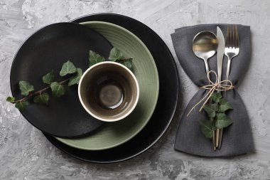 Masa dekorları çok şık. Tabaklar, çatal bıçak takımı, peçete ve çiçek dekoru.