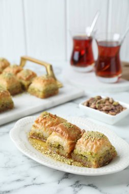 Lezzetli taze baklava, doğranmış fındık ve beyaz mermer masada bal. Doğu tatlıları