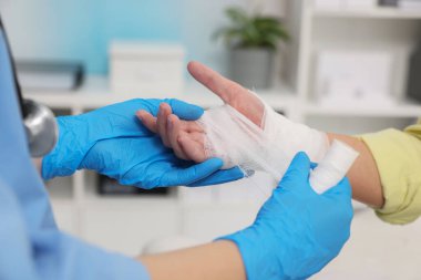 Hastanın elini saran doktor hastanede yanmış, yakın plan.