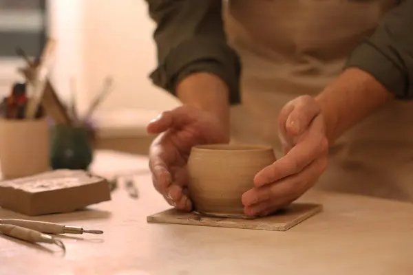 Clay crafting. Man making bowl at table, closeup