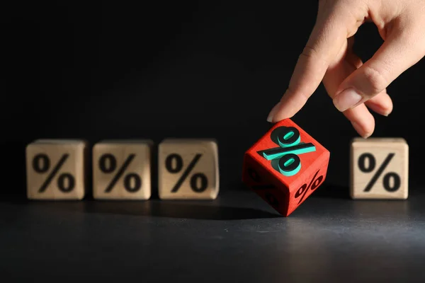 Best mortgage interest rate. Woman touching red cube with percent sign on black table, closeup