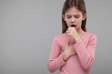 Hasta kız gri arka planda öksürüyor, mesaj için yer var.