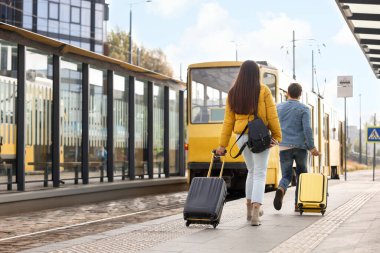 Geç kalmak. Bavullu çift tramvaya doğru yürüyor, arka manzara. Metin için boşluk