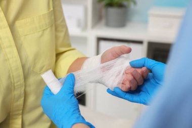 Hastanın elini saran doktor hastanede yanmış, yakın plan.