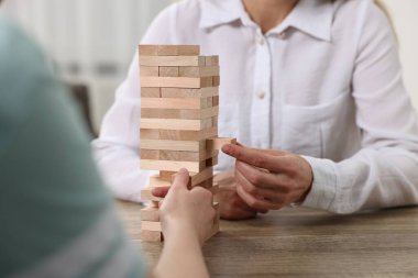 İnsanlar içeride, ahşap masada Jenga kulesi oynuyorlar.