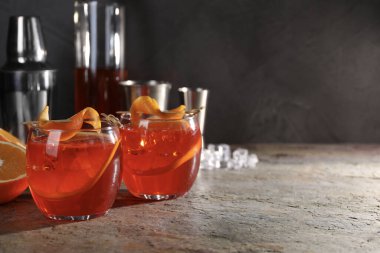 Aperol sprey kokteyli, buz küpleri ve gri desenli masada portakal dilimleri, metin için boşluk.