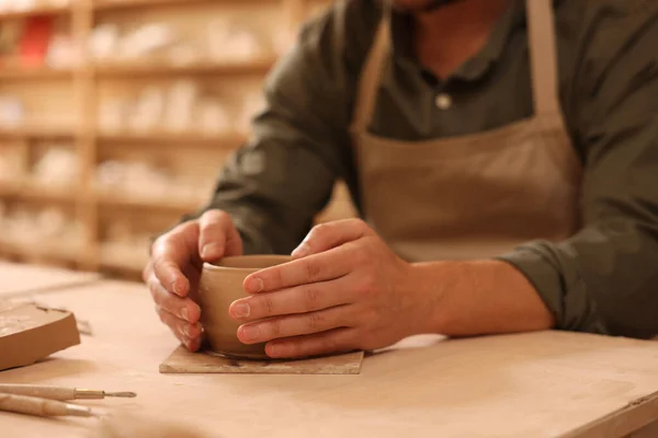 Clay crafting. Man making bowl at table indoors, closeup