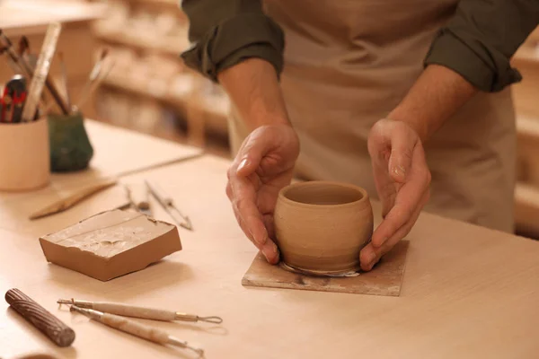 Clay crafting. Man making bowl at table indoors, closeup
