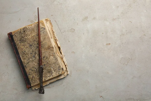 Magic wand and old book on light textured background, top view. Space for text
