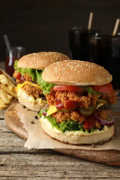 Delicious burgers with crispy chicken patty on wooden table