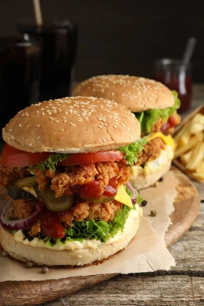 Delicious burgers with crispy chicken patty on wooden table, closeup
