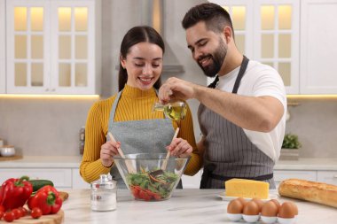 Genç ve güzel bir çift mutfakta birlikte yemek pişiriyor.