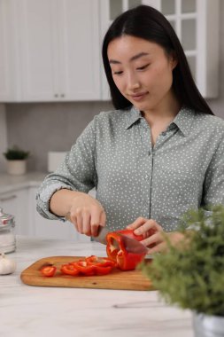 Yemek pişirme süreci. Güzel bir kadın mutfakta beyaz tezgahta dolma biber kesiyor.