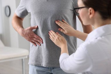 Gastroenterolog klinikte mide ağrısı olan hastayı muayene ediyor.