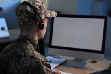 Askerlik. Kulaklıklı asker ofiste çalışıyor, mesaj için yer var.