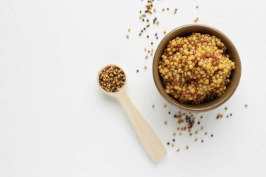 Kâsede taze tahıllı hardal ve beyaz masada kuru tohumlar. Metin için boşluk