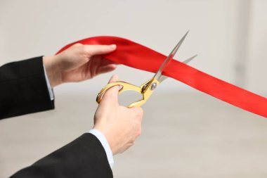 Kırmızı kurdeleyi içeride makasla kesen kadın, yakın plan.