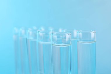 Laboratuvar analizi. Açık mavi arkaplanda sıvı örnekleri olan test tüpleri, yakın plan