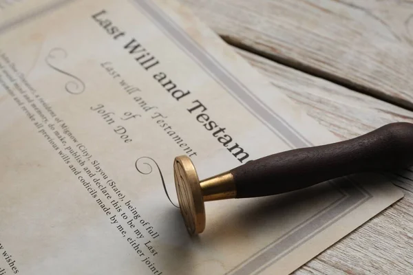 Last Will and Testament with wax stamp on wooden table, closeup