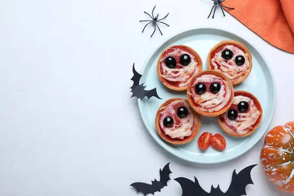 Cute monster tartlets served on white table, flat lay with space for text. Halloween party food