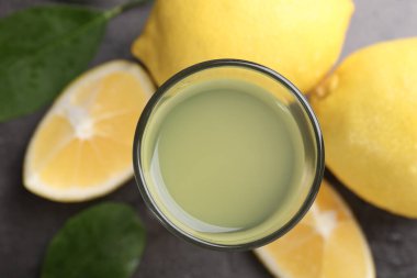 Lezzetli limoncello likörü, limonlar ve yeşil yapraklar masanın üstünde.