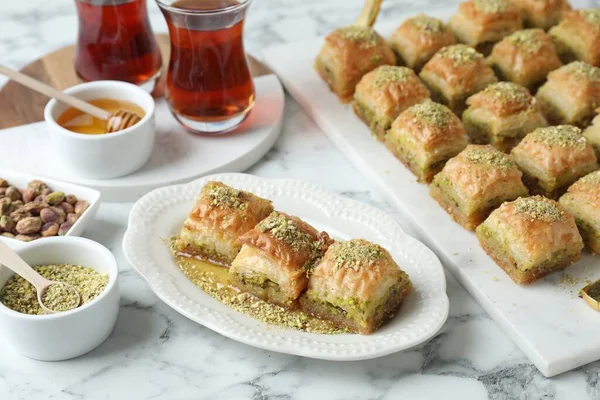 Delicious fresh baklava with chopped nuts and honey served on white marble table. Eastern sweets
