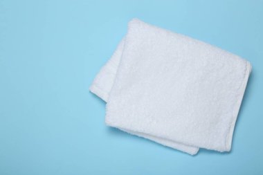 Açık mavi arka planda beyaz havlu, üst manzara. Metin için boşluk