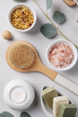 Farklı spa ürünleri, yanan mum ve okaliptüs dallarının bulunduğu düz bir kompozisyon.