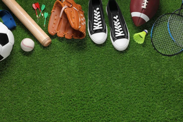 Different sport tools on green grass, flat lay. Space for text