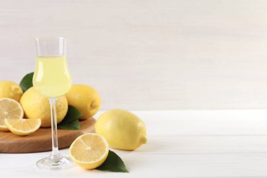 Lezzetli limoncello, limon ve yeşil yapraklı beyaz ahşap masa. Metin için boşluk